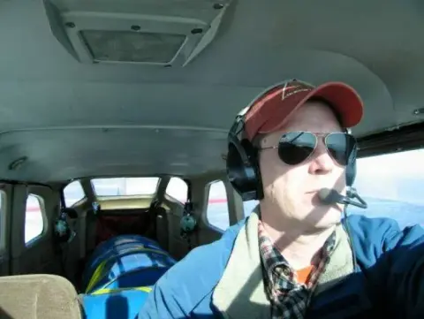 A pilot in a headset and sunglasses in the cockpit