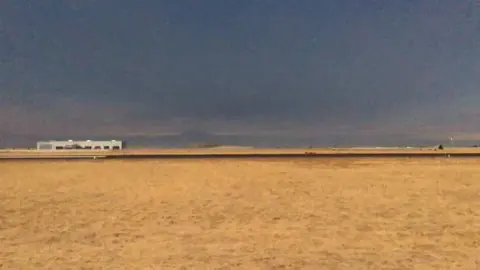 A dry field under a darkened eclipse sky