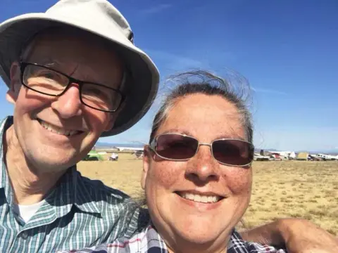 A man and a woman taking a sunny selfie at the field