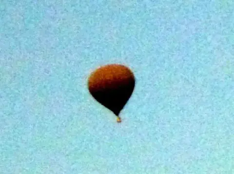 A hot air balloon high in a hazy sky