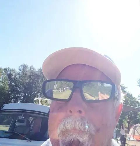 A man in sunglasses taking a selfie outdoors
