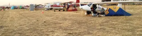 Airplanes and tents parked on a dry grass field