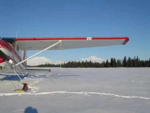 A red and white airplane parked on a snowy field