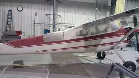 A red and white high-wing airplane inside a hangar