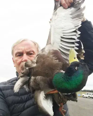 A man holding up a duck