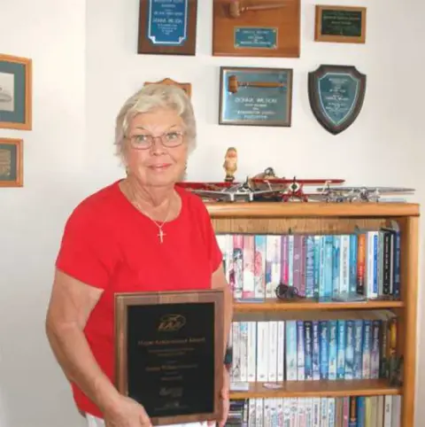 A woman holding a plaque in front of a bookcase