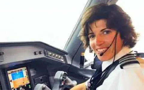 A smiling woman pilot in the cockpit of a jet
