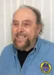 A smiling man with a white beard in a blue shirt