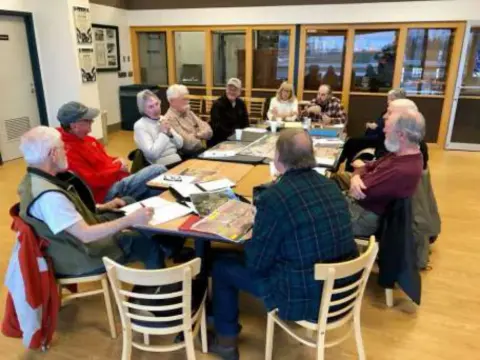 Members seated around tables at a meeting