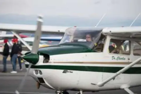 A white and green high-wing airplane on the ramp