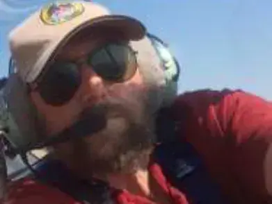 A bearded man in a headset and sunglasses