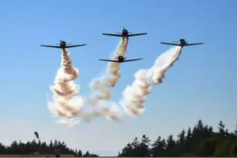 Four airplanes trailing smoke in formation