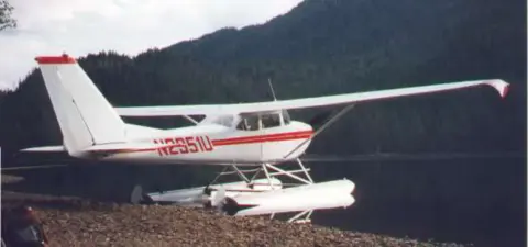 A white high-wing floatplane on a beach