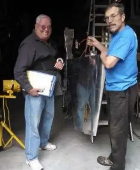 Two men looking over parts in a workshop
