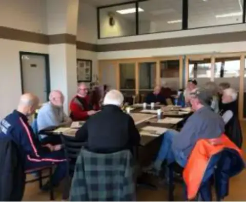 Chapter members seated around tables at a planning meeting in a room with tall windows