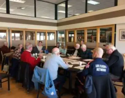 Another view of the planning meeting, members seated around long tables