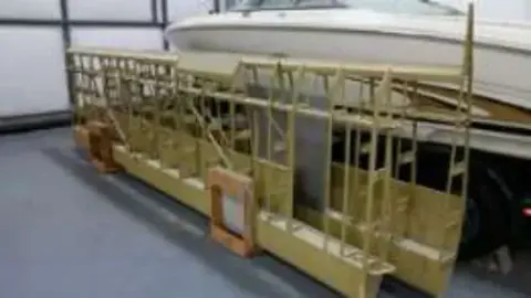 A wooden wing structure on a stand in a hangar
