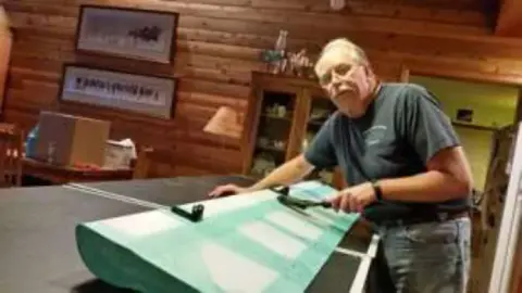 A man working on a painted green wing panel