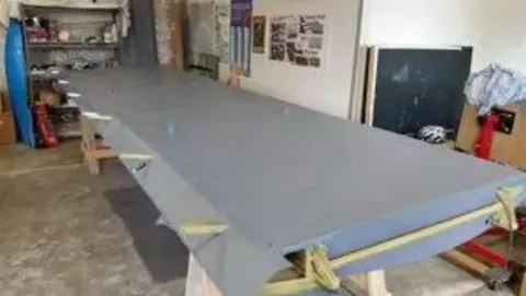 A gray painted wing on sawhorses