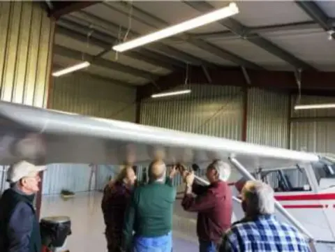 People in a hangar gathered around an airplane