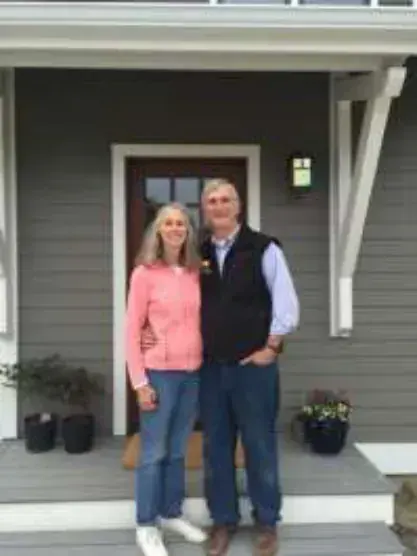 A man and a woman standing on the porch of a house
