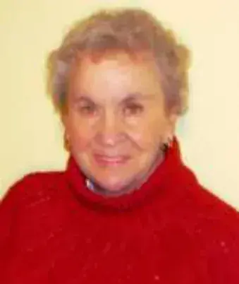 A smiling white-haired woman in a red sweater