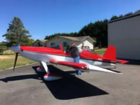 A red and white low-wing airplane on the ramp