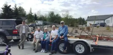 Ray, Ken, Donna, Ernie and Peter sitting on the trailer with the Smith Mini Biplane