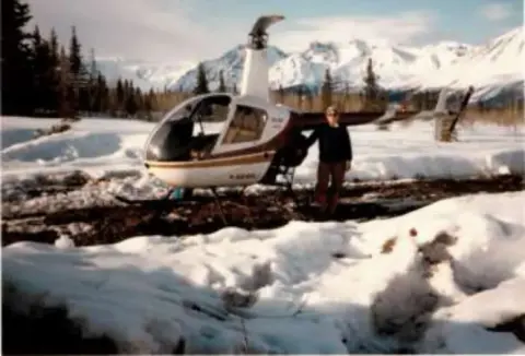 A small helicopter parked in a snowy mountain clearing