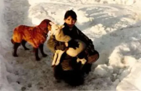A person in snow hugging a large brown dog