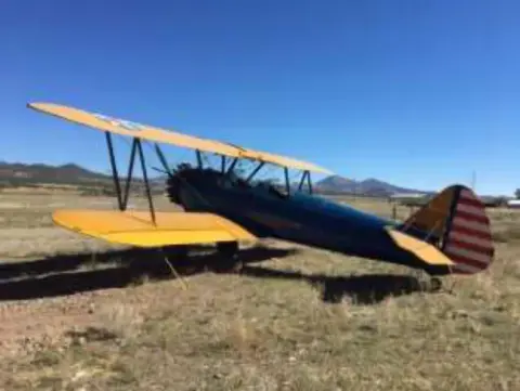 A blue and yellow biplane parked on the grass