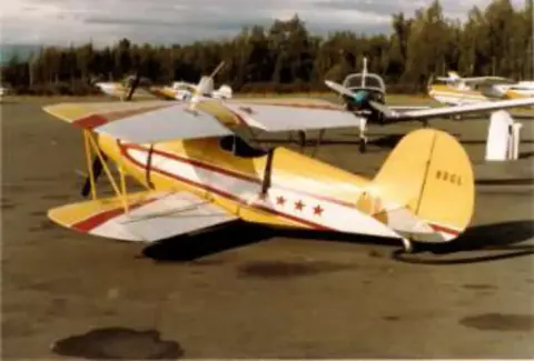A yellow and red biplane on the ramp with other airplanes