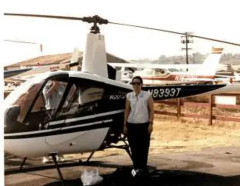 A woman standing beside a white helicopter