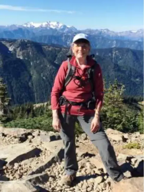 A woman hiker on a rocky ridge with mountains behind