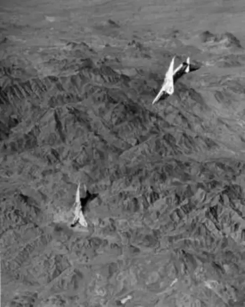 Two jets flying low over mountains, in black and white