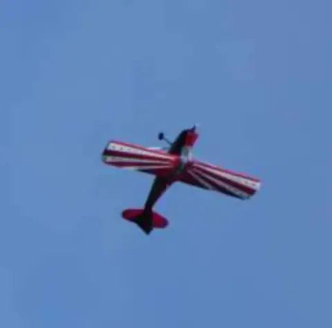 A red, white and blue aerobatic airplane in flight