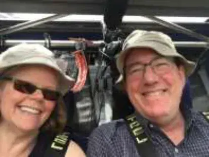 A smiling woman and man in sun hats taking a selfie in a cockpit