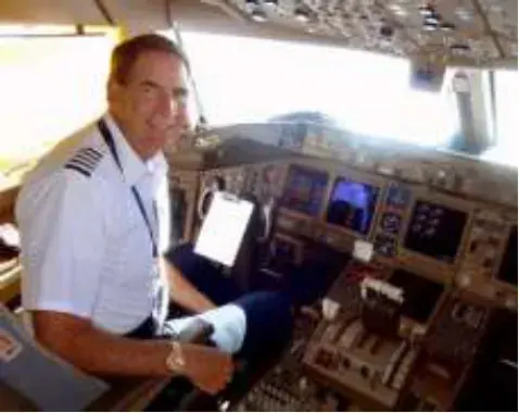 A pilot in uniform at the controls of an airliner flight deck