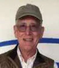 A smiling older man in a green cap and glasses
