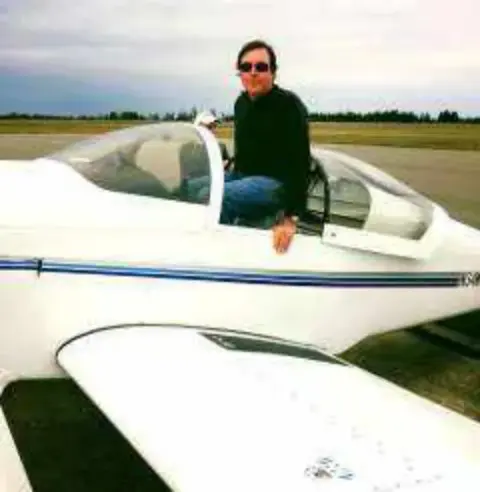 A man sitting on the wing of a white airplane