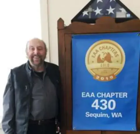 A man standing beside an EAA Chapter 430 banner