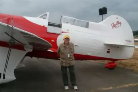 A man beside a red and white aerobatic airplane