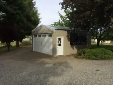 A small garage-style building under trees