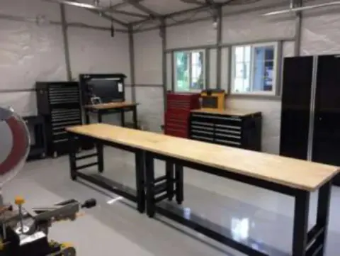 An empty workshop with a long workbench and tool chests