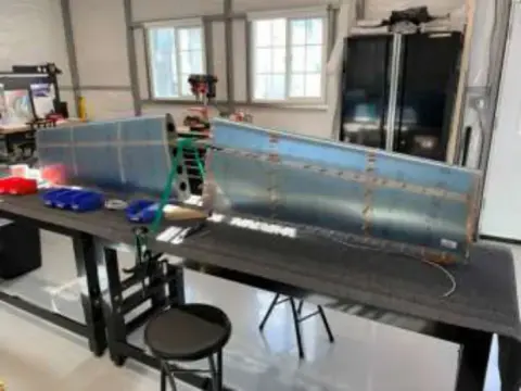 Workbenches with tools and a wing skin in a shop