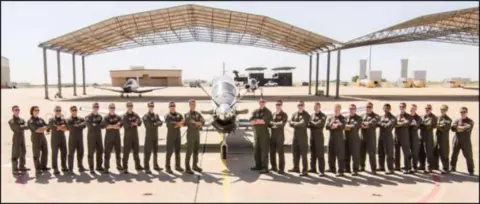 A row of cadets standing under a hangar shade structure