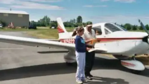 Two people talking beside a low-wing airplane on the ramp
