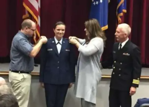 A young woman in uniform receiving her wings at a ceremony