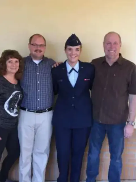 A young woman in uniform with family members