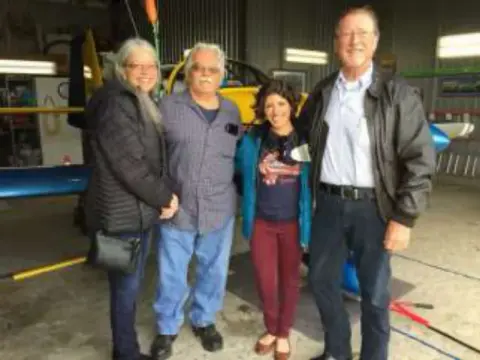 Four people standing together in a hangar